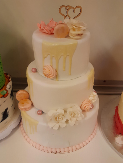 Hääkakkukilpailun 3. sijan voittaneessa kakussa on Macarons-leivoksia, valkoisia ruusuja ja keltaista kuorrutetta koristeena. Kakun päällä on kaksi sydäntä.