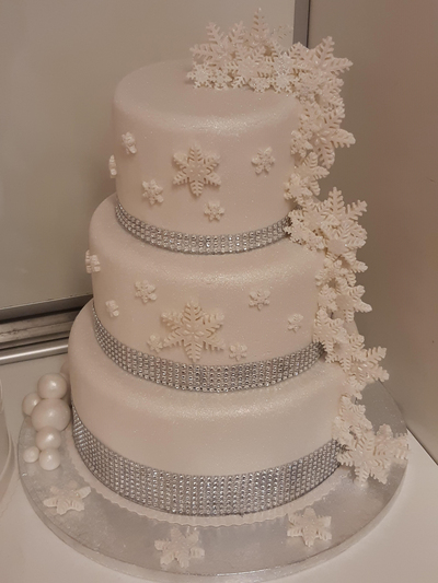 Hääkakkukilpailun 2. sijan saavuttanut kakku on talvisen valkoinen. Siinä on hopeiset nauhat ja lumihiutaleita koristeena.