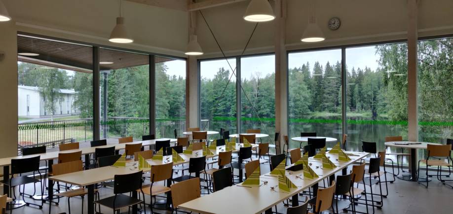 Metsäopiston salissa pöydät valmiina opiskelijoita varten. Suurista ikkunoista avautuu näkymä Sahalahden rantaan.