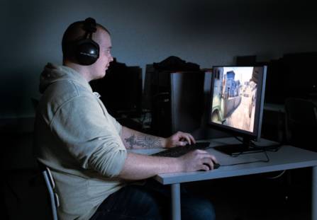 Joonas Leväniemi pelaa kuulokkeet päässä tietokoneella eSports-peliä.