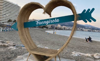 Kuva Espanjasta Fuengirolasta. Kuvassa iso sydän, jossa istumiseen penkkki sekä sininen nuoli, jossa lukee valkoisella kaunokirjoitettunaFuengirola.