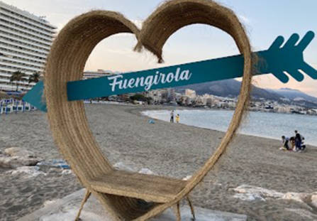 Kuva Espanjasta Fuengirolasta. Kuvassa iso sydän, jossa istumiseen penkkki sekä sininen nuoli, jossa lukee valkoisella kaunokirjoitettunaFuengirola.