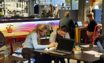 People working in cafe. There are laptos on tables.