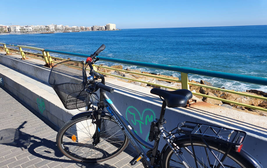 Kuvassa polkupyörä merenrantakadun varrella. Taustalla meri ja kaupunki.