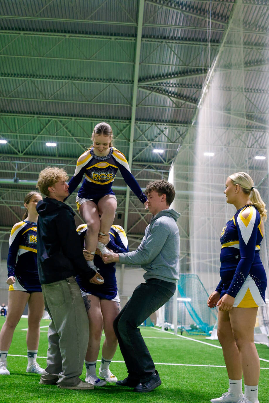 Opiskelijat nostavat cheerleaderia ylös.
