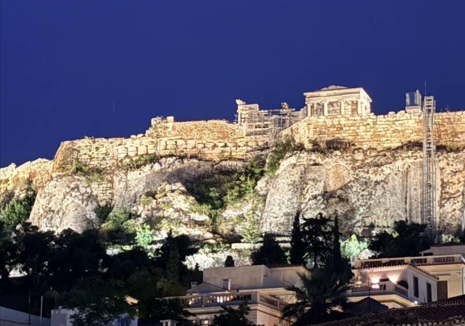 Acropolis-kukkulan päällä on muinaiset rakennukset. Kukkula on valaistu iltahämärässä.