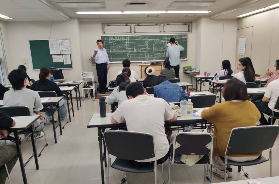 Japanilaisessa luokkahuoneessa ei ole tietokoneita ja luokan edessä on liitutaulu.