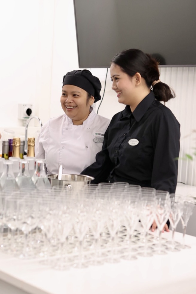 Ravintola- ja catering-alan opiskelija iloisena tarjoilemassa.